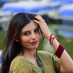 Beautiful woman in traditional Indian dress posing gracefully beside water.